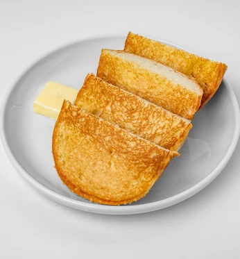 Toasted pandesal slices with a pat of butter on a white plate