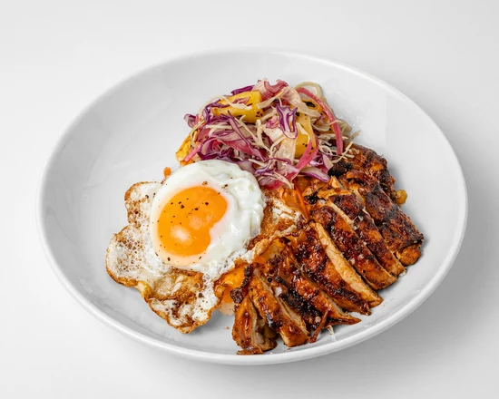 BBQ chicken rice bowl with sliced grilled chicken, a fried egg and pineapple slaw in a white bowl