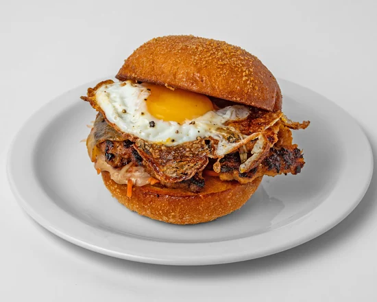 Pork breakfast sandwich with a sausage patty, fried egg and pickled papaya on a pandesal bun