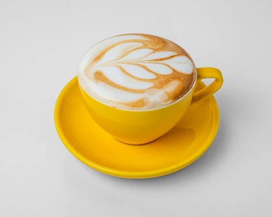 Cappuccino with latte art in a yellow cup and saucer