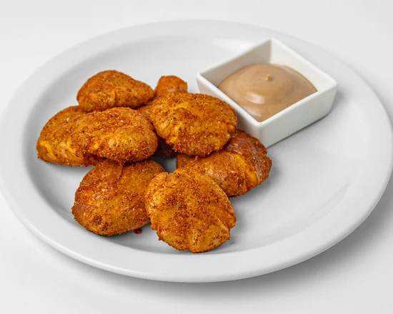 Smashed herb fried potatoes with a dipping sauce on a white plate
