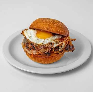Pork breakfast sandwich with a sausage patty, fried egg and pickled papaya on a pandesal bun