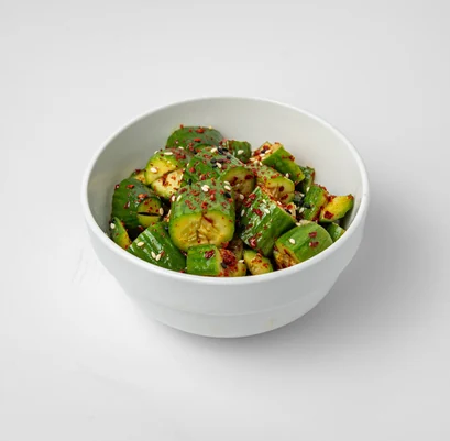 Smashed cucumber salad with chilli flakes and sesame seeds in a white bowl