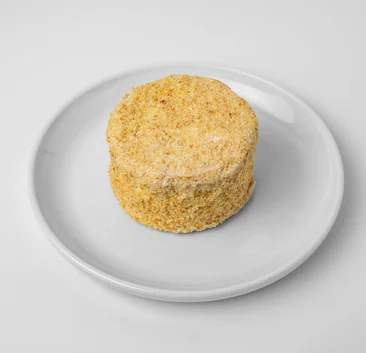 Sylvanas, a round cashew meringue dessert coated in crumbs, on a white plate